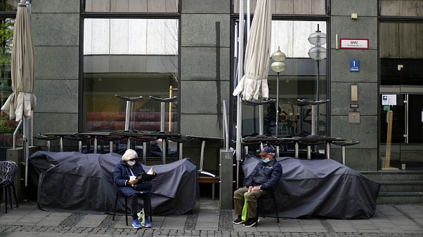 An elderly couple sit outside a closed bar in Munich, Germany An elderly couple sit outside a closed bar in Munich, Germany