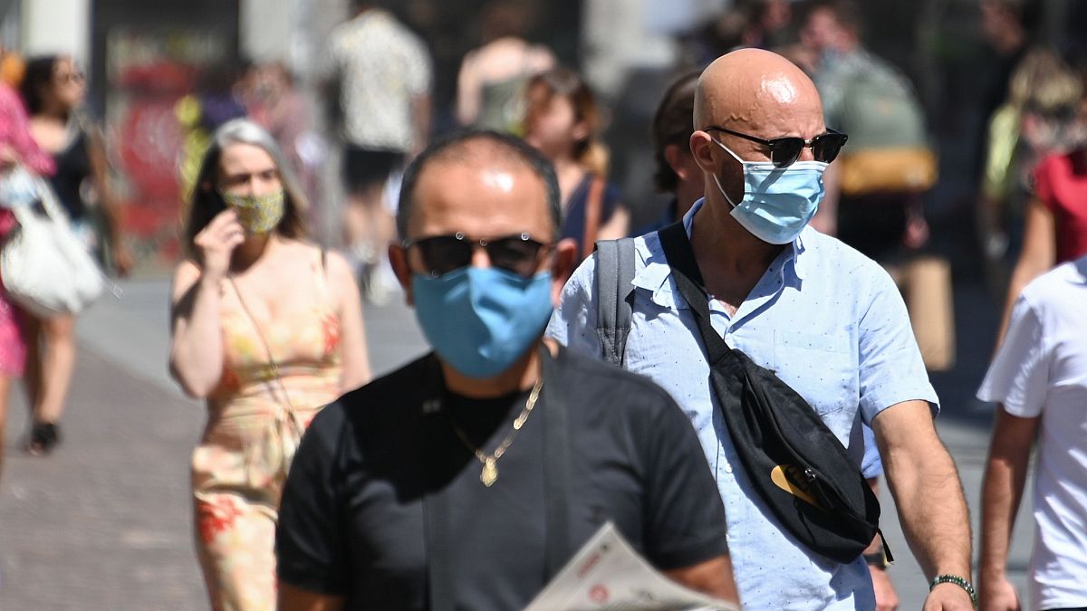 People wearing protective masks walk on a street in Lille, France