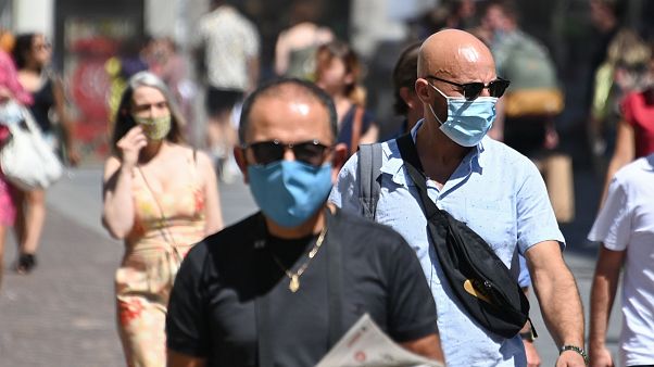 People wearing protective masks walk on a street in Lille, France People wearing protective masks walk on a street in Lille, France