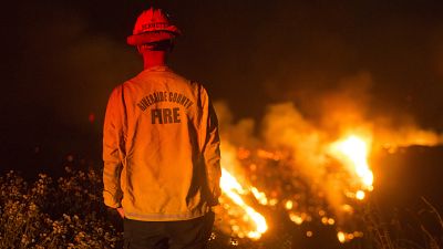 Un bombero observa un incendio de matorrales en el incendio de Apple en Banning, California, el sábado 1 de agosto de 2020.