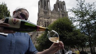 A waitress serves a glass of champagne at La Grande Georgette restaurant in front of the cathedral in Reims, onTJuly 28, 2020.