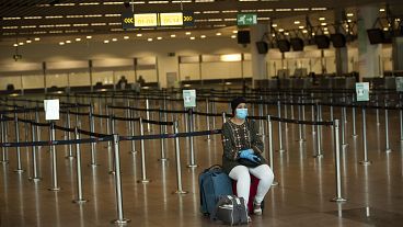 A woman sits at the almost empty departures hall at the Zaventem international airport in Brussels, Wednesday, July 29, 2020.