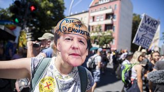 Una mujer lleva una máscara de Angela Merkel con la inscripción "adíos democracia" en la manifestación contra las restricciones en Berlín, Alemania, el 1 de agosto, 2020.