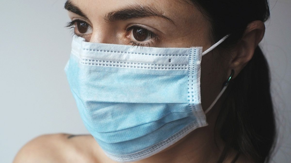 A woman wears a disposable face mask.