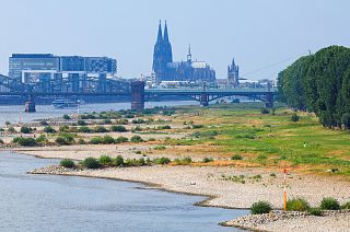 Rhine bank at low tide in Cologne, Germany. The Rheinauhafen with the Crane Buildings and Cologne Cathedral in the background.