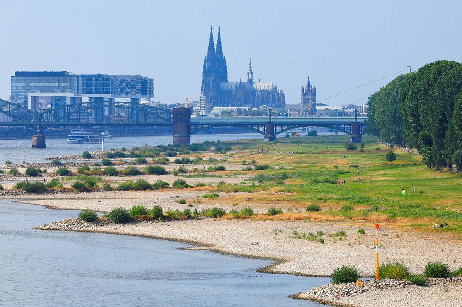 Rhine bank at low tide in Cologne, Germany. The Rheinauhafen with the Crane Buildings and Cologne Cathedral in the background.