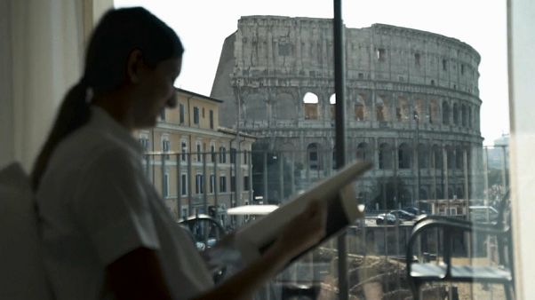 Una turista in una camera di hotel a Roma, con il Colosseo sullo sfondo Una turista in una camera di hotel a Roma, con il Colosseo sullo sfondo