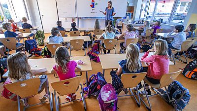 Teacher Francie Keller welcomes the pupils of class 3c in the Lankow primary school to the first school day in Schwerin, Germany, Monday, Aug. 3, 2020.