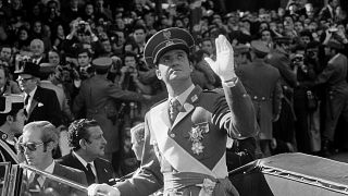 King Juan Carlos I, standing up in an open car as he drives through Madrid after his proclamation waves up, Nov. 22, 1975. 