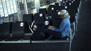 Una pasajera, con una máscara facial para protegerse de la propagación del coronavirus, se sienta antes de embarcar en su vuelo