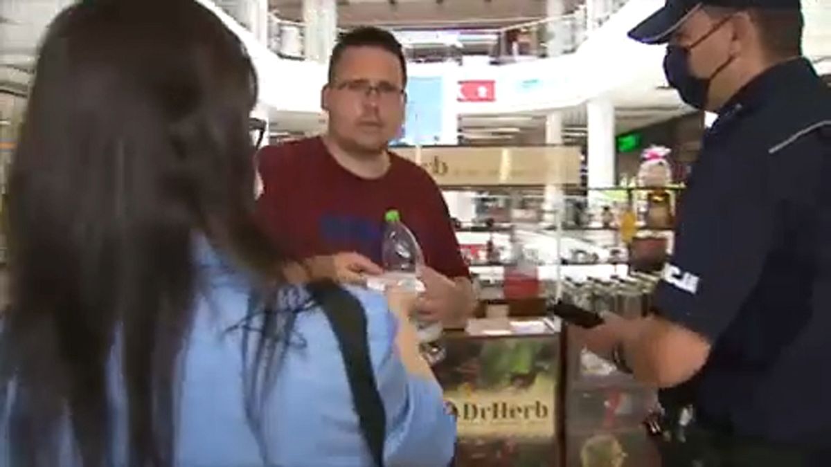 Rendőr ellenőrzi a maszkviselést egy lengyelországi bevásárlóközpontban