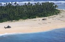 In this photo provided by the Australian Defence Force, three men stand the beach on Pikelot Island in the Federated States of Micronesia