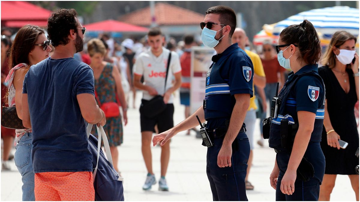 أفردا من الشرطة الفرنسية ينصحون مواطنين بارتداء الكمامات في بياريتز، جنوب غرب فرنسا