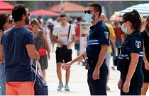 أفردا من الشرطة الفرنسية ينصحون مواطنين بارتداء الكمامات في بياريتز، جنوب غرب فرنسا