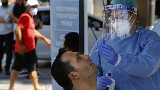 A health worker carry out coronavirus tests on a man outside a municipal administration building in southern coastal city of Limassol, Cyprus