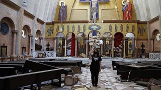 Nő készít képeket egy megsérült keresztény templomban szerdán