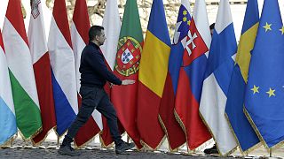 A man walks by flags of the EU member states