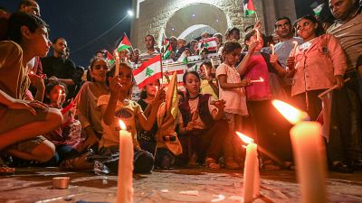 Palestinians attend a candle light vigil in Rafah in support of Lebanon