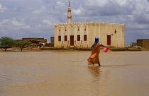 A Sudanese woman crosses a flooded area, as a result of flooding and torrential rain, in the town of Osaylat.