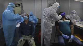 Indian health volunteers take swab samples for at a COVID-19 test study camp at a government hospital in New Delhi.