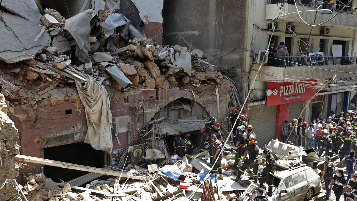 طاقما إنقاذ، أحدهما لبناني والآخر فرنسي أمام مبنى انهار جراء الانفجار بالقرب من مرفأ بيروت 