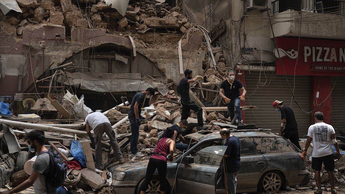 أشخاص يزيلون حطام منزل دمره انفجار الثلاثاء في ميناء بيروت، لبنان، وفرق الإنقاذ تبحث عن جثث بين الأنقاض