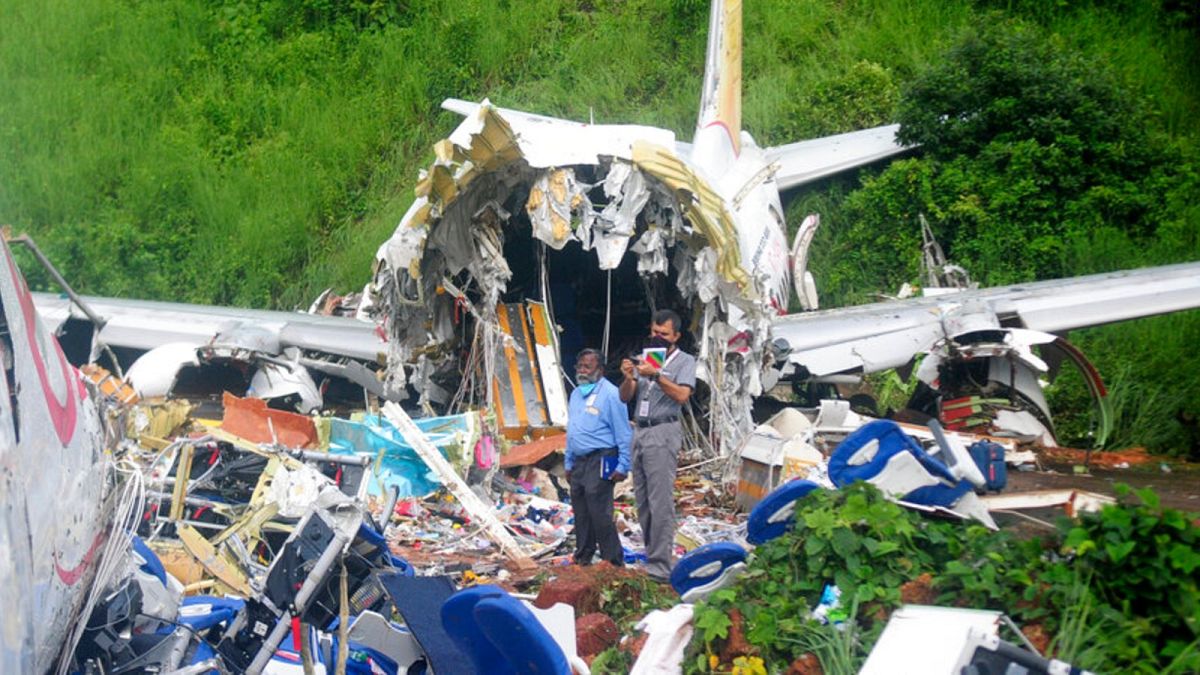 Officials stand on the debris of the Air India Express flight that skidded off a runway while landing at the airport in Kozhikode, Kerala state, India, Saturday, Aug. 8, 2020