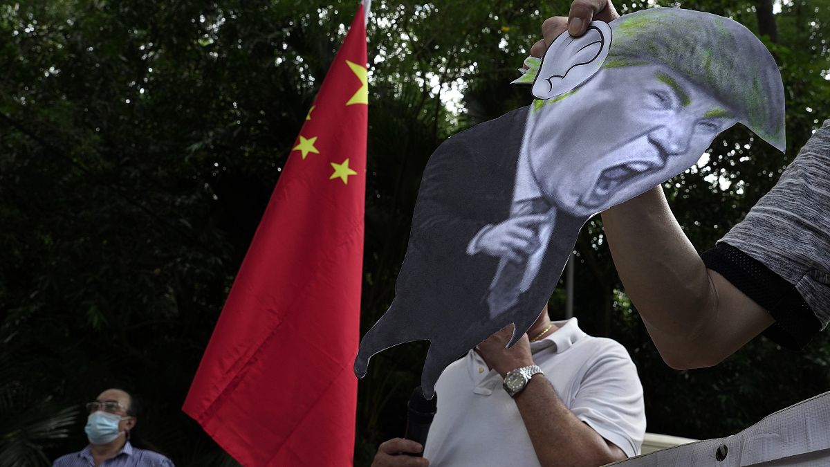 تظاهرکنندگان حامی چین،‌ با کاریکاتوری از دونالد ترامپ، مقابل سفارت آمریکا در هنگ کنگ