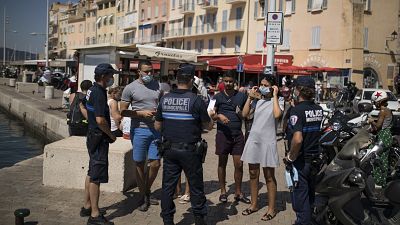 Police give masks to tourists walking along the Saint-Tropez port.