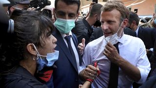 French President Emmanuel Macron, right, speaks with a woman as he visits the Gemayzeh neighborhood, which suffered extensive damage from the explosion in Beirut.