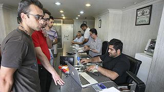 Iranians exchange currencies in a money exchange bureau, in downtown Tehran, Iran
