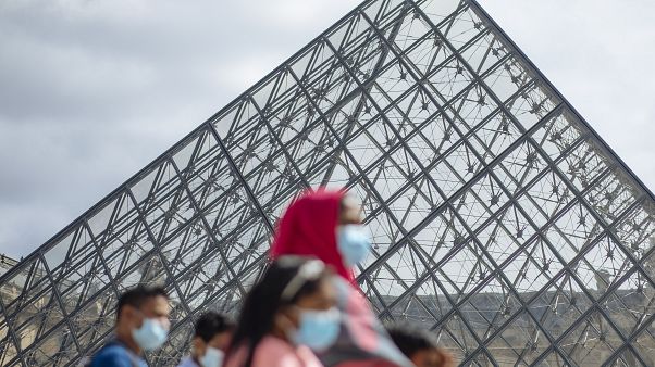 A family wearing face masks walk past the Louvre Museum in Paris on Saturday A family wearing face masks walk past the Louvre Museum in Paris on Saturday