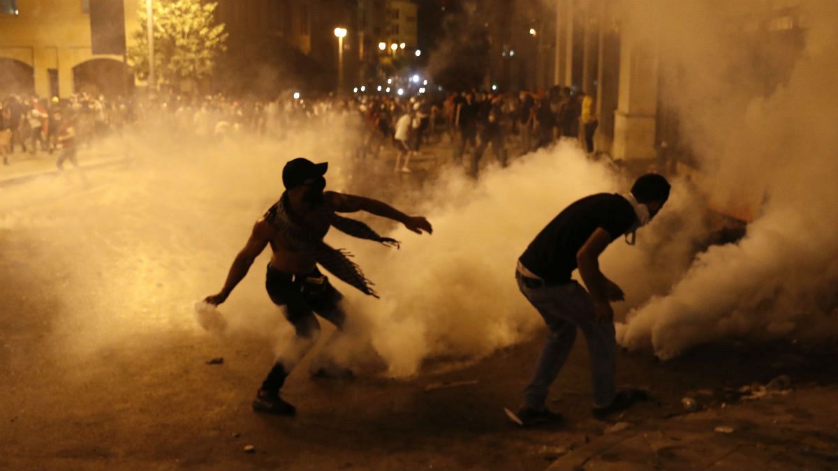 A protester turns back tear gas canister against the Lebanese riot police