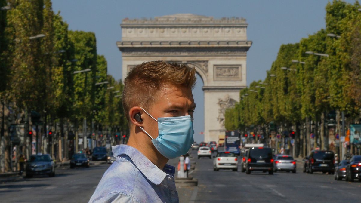 A man wearing a masks to prevent the spread of COVID-19 crosses the Champs Elysees avenue in Paris, Sunday, Aug 9, 2020. 