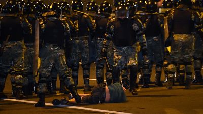 A man lies on the ground in front of riot police during a protest after polls closed in Belarus' presidential election, in Minsk on August 9, 2020.
