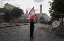 Egy nő libanoni zászlót lenget szemben a rendőrsorfallal