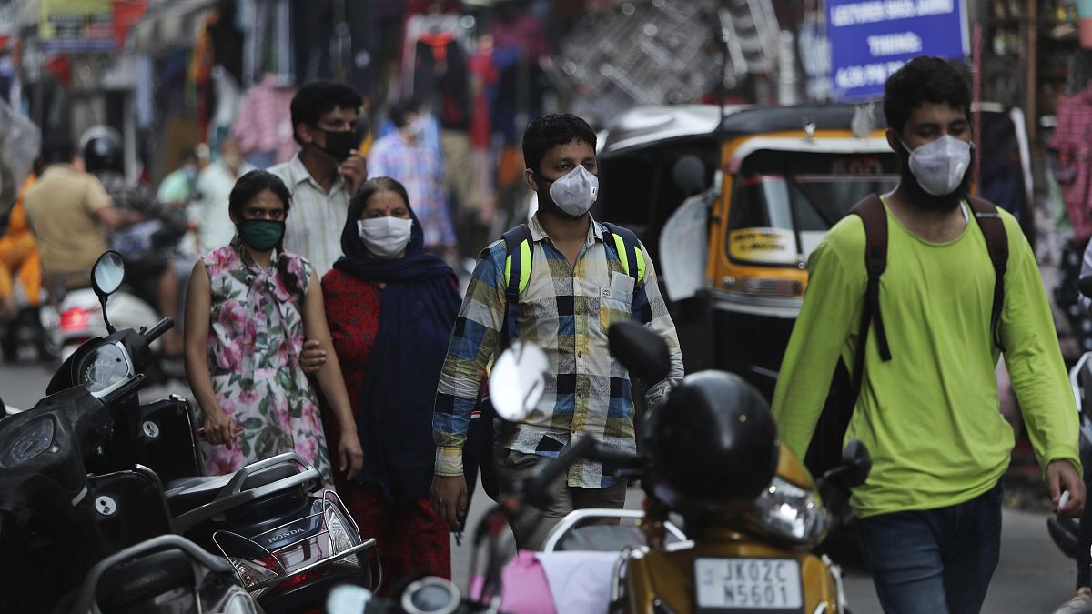 Indians wearing face masks as a precaution against the coronavirus walk at a market in Jammu, India, Monday, Aug 10, 2020.
