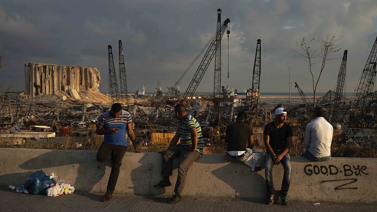 People sit near the site of last week's explosion that hit Beirut's port