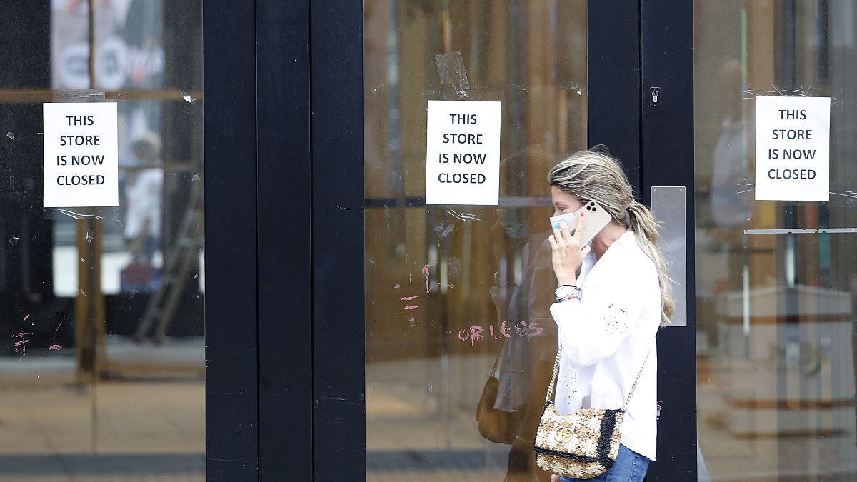 A woman walks by a closed store, in London, Thursday, July 16, 2020. Figures show UK employment suffered the biggest three-month decline since the 2009 recession. 