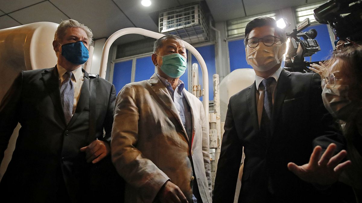 Hong Kong media tycoon and newspaper founder Jimmy Lai, center, walks out from a police station after being bailed out in Hong Kong