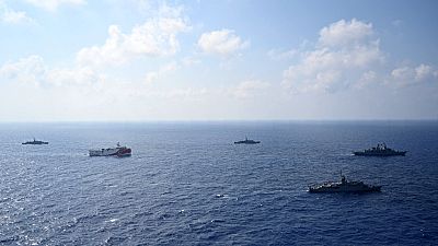 In this photo provided by the Turkish Defense Ministry, Turkey's research vessel, Oruc Reis, in red and white, is surrounded by Turkish navy vessel