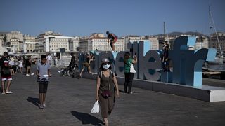 A woman walks along Marseille's Old Port, southern France, Friday Aug 7, 2020. 