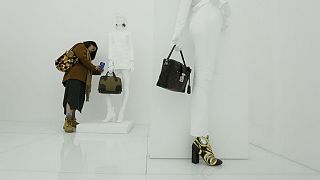 A visitor takes photo of a bag at an exhibition by french luxury brand Louis Vutton in Beijing