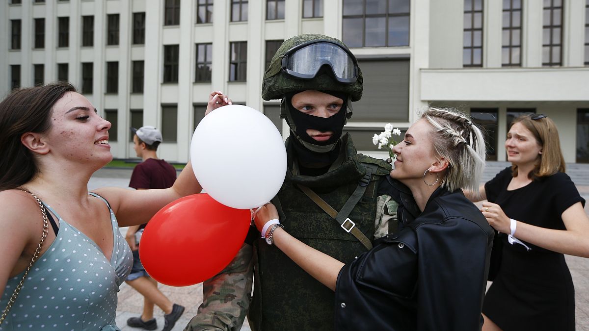 Mujeres abrazan a un soldado que vigila el edificio del Gobierno en Minsk en una protesta pacífica conra la represión policial