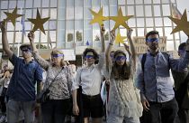 Protesters hold EU stars and keep their eyes closed in front of the German Embassy in Sofia, Bulgaria, Wednesday, Aug. 12, 2020.