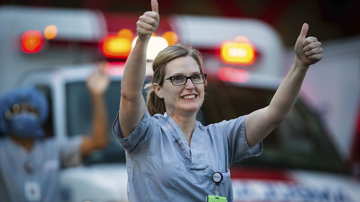 A healthcare worker at St. Paul's Hospital acknowledges applause and cheers from people outside the hospital
