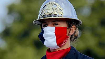 a firefighter wears a face mask with the colors of the French flag, prior to the Bastille Day parade 