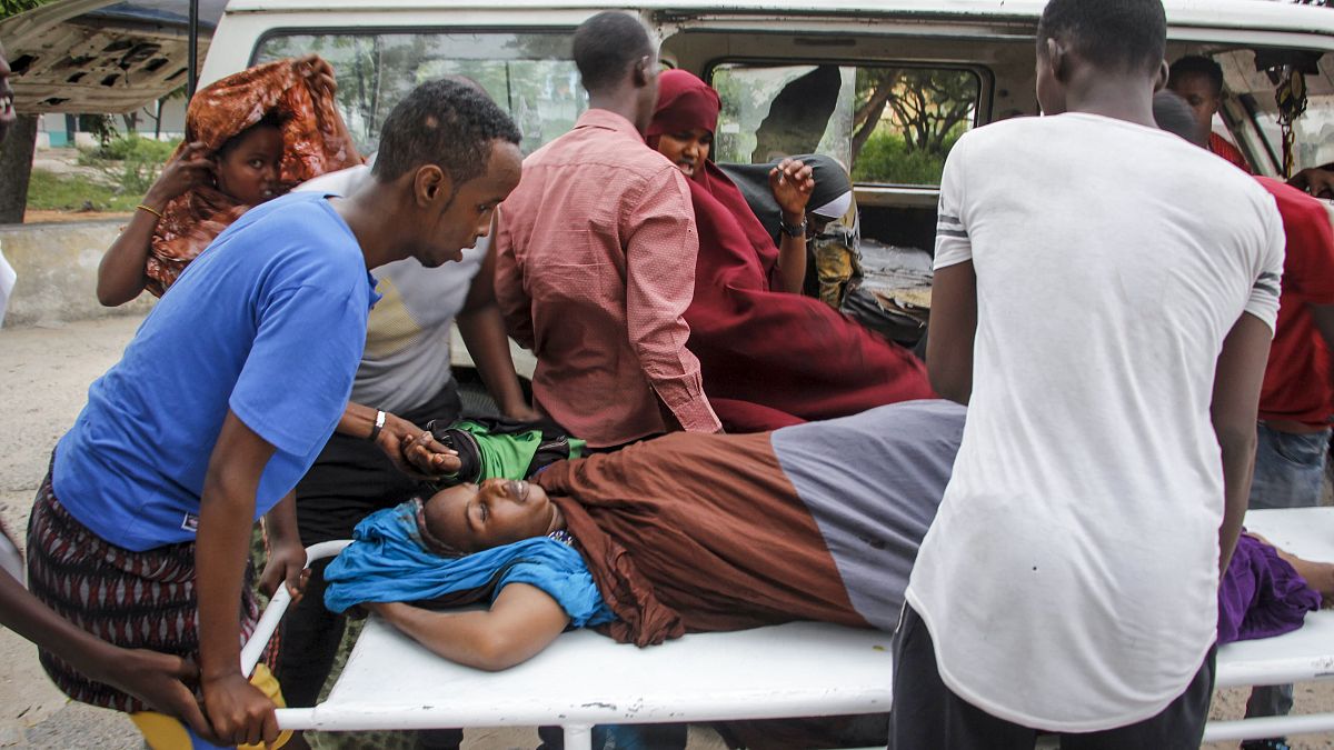 People help a civilian woman, who was wounded when a powerful car bomb blew off the security gates to the Elite Hotel, in Somalia Sunday, Aug. 16, 2020.