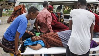 People help a civilian woman, who was wounded when a powerful car bomb blew off the security gates to the Elite Hotel, in Somalia Sunday, Aug. 16, 2020.