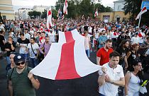 People carry an old Belarusian national flag during an opposition rally in Minsk, Belarus, Monday, Aug. 17, 2020
